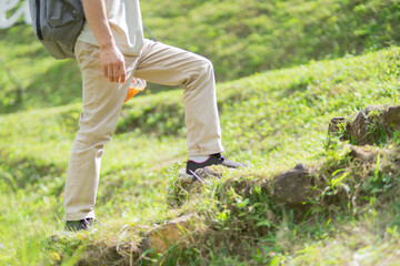 A man hikes through lush forests towards a waterfall, enjoying exploration during retirement. Adventure, relaxation, sustainable tourism, the wonders of nature, outdoor backpacking, and recreation.