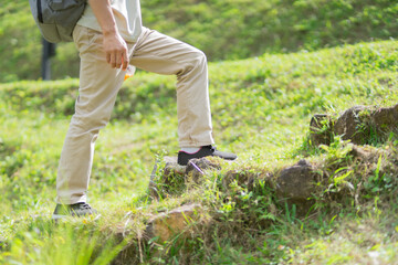 A man hikes through lush forests towards a waterfall, enjoying exploration during retirement. Adventure, relaxation, sustainable tourism, the wonders of nature, outdoor backpacking, and recreation.