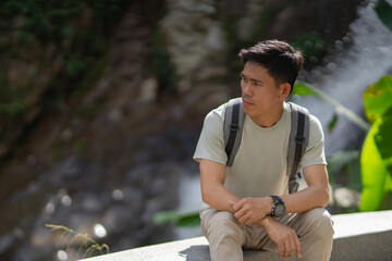 A man hikes through lush forests towards a waterfall, enjoying exploration during retirement. Adventure, relaxation, sustainable tourism, the wonders of nature, outdoor backpacking, and recreation.