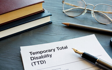 Temporary Total Disability TTD Document on Office Desk with Pen and Glasses