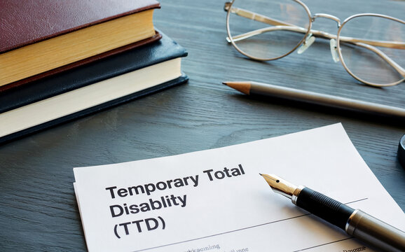 Temporary Total Disability TTD Document on Office Desk with Pen and Glasses