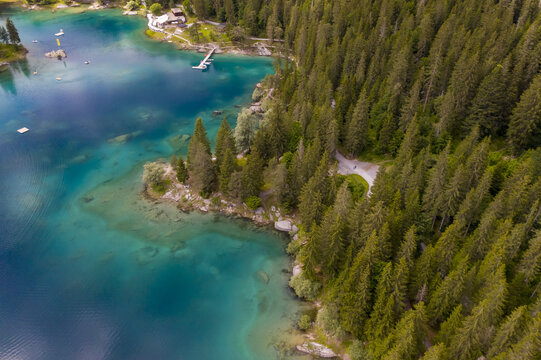 Aerial view of the turquoise lake's edge meeting the dense green forest, a vibrant contrast of natural beauty, Flims, Grisons, Switzerland.