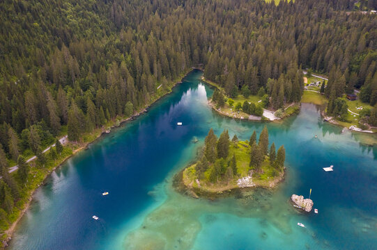 Aerial view of the shimmering turquoise waters of Caumasee, fringed by dense evergreen forests and a small island, creating a stunning contrast of colors, Flims, Grisons, Switzerland.