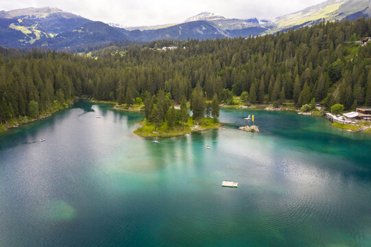 Aerial view of the shimmering turquoise waters of Lake Cauma nestled amidst the verdant forest and towering mountains, a scene of tranquil beauty, Flims, Grisons, Switzerland.