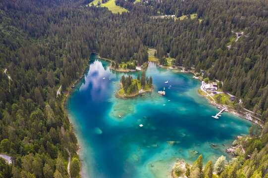 Aerial view of the shimmering Cauma Lake turquoise lake reflecting the sky, surrounded by dense evergreen forests, a haven of tranquility and vibrant natural beauty, Flims, Grisons, Switzerland.
