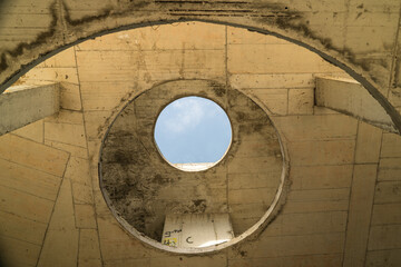 View of a concrete structure with a circular opening revealing a patch of pale blue sky, creating a stark contrast of textures, Costa del croco, Tsarevo, Bulgaria.