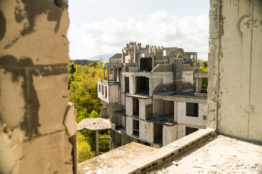 View of a concrete skeleton of an unfinished building, rising against the backdrop of a lush green forest under a sky, Costa del croco, Tsarevo, Bulgaria.