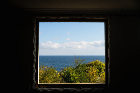 View of a tranquil seascape framed by a dark window, the blue sea contrasting with the green vegetation, Costa del croco, Tsarevo, Bulgaria.