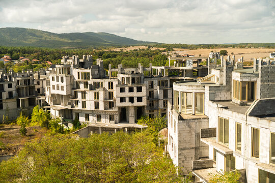 View of unfinished concrete buildings standing starkly against the backdrop of rolling hills and a cloudy sky, Costa del croco, Tsarevo, Bulgaria.
