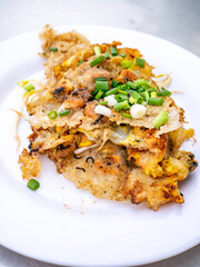 Crispy Thai Oyster Omelette (Hoi Tod) served with fresh bean sprouts and spring onions on a white plate
