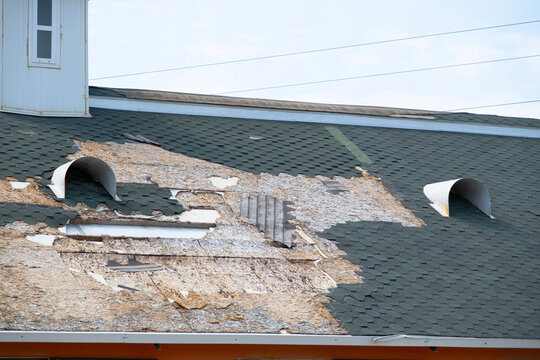 Damaged roof showing exposed underlayment and missing shingles presenting potential for water leakage and requiring urgent repair or renovation