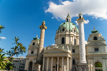 View of Karlskirche's baroque architecture rises majestically against a vibrant blue sky dotted with fluffy white clouds, Vienna, Vienna, Austria.