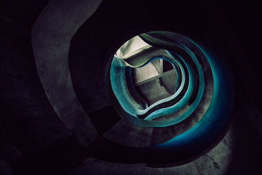 View of a winding staircase, a dark vortex of steps illuminated with an eerie blue glow, descending into the unknown, Crevarska Strana, Sisak-Moslavina County, Croatia.