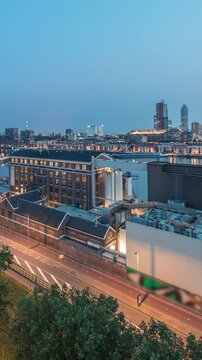 Aerial panoramic view over towers in Maashaven night to day transition timelapse with moored ships, Katendrecht and Maas River, Rotterdam. Traffic near factory converted into office and event space