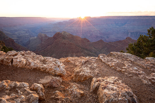 Rocky rugged canyon overlook with golden sun starburst on horizon