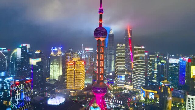 Aerial panoramic view of the Oriental Pearl Tower and numerous modern, brightly illuminated skyscrapers defining the urban skyline of Shanghai, China.