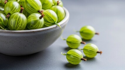 Fresh green gooseberries in bowl on grey table, closeup