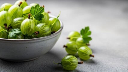 Fresh green gooseberries in bowl on grey table, closeup