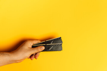 Hand presenting stack of desktop RAM modules on yellow background. High quality photo