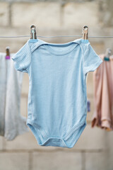Blue infant bodysuit air drying in natural light