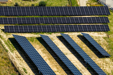 Aerial view of solar panels renewable energy farm in a rural environment, located on a raw ground stands