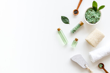 Obraz na płótnie Canvas Spa pedicure accessories and organic cosmetics products - tea tree essential oil and sea salt near green leaves top view