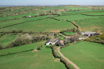 A northward view from Carreg Cennen Castle in Carmarthenshire, Wales, overlooking a rural landscape of rolling green fields dotted with scattered farm buildings
