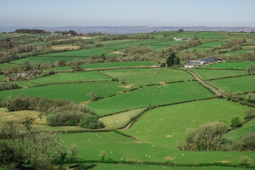 A northward view from Carreg Cennen Castle in Carmarthenshire, Wales, overlooking a rural landscape of rolling green fields dotted with scattered farm buildings