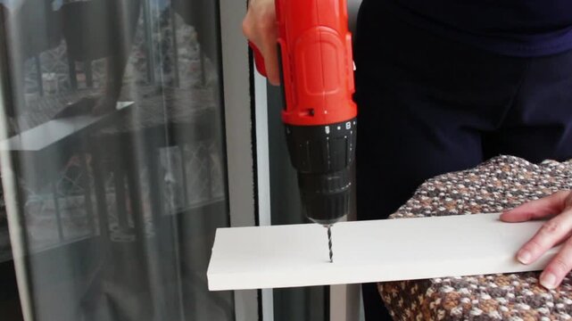 Woman failing to drill a hole in a wooden board due to a low battery power tool. Horizontal video with copy space, suitable for woodworking tutorial, diy craft projects and carpentry content.