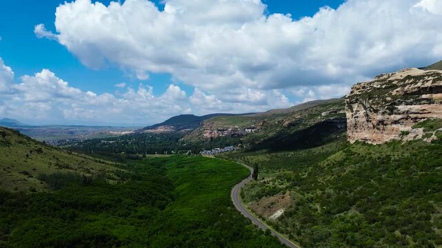Camera rising up over the road leading to Clarens South Africa with the Maluti Mountains on both sides 4K Aerial Video.