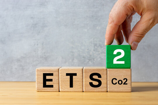 ETS 2 European Trading System. Business, environmental concept. Text ETS on wooden blocks and a businessman's hand adding a cube with the number two. New System for Trading in Carbon Emission Permits.