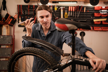 Mechanic repairing bicycle and listening to voice message using smartphone to consult with AI