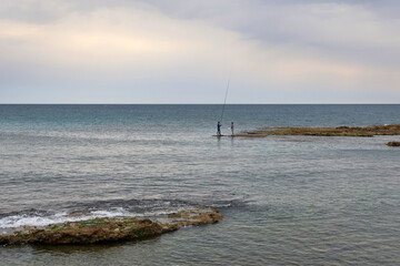 Fishermen on a Rock Formation in Calm Sea