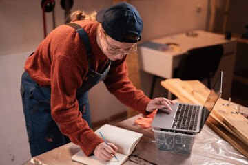 Woodworker woman typing laptop shopping app online working in her. carpenter female buying on website. Small business