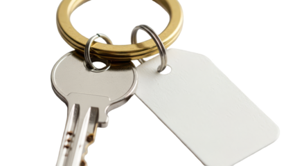 A silver key with a blank white tag on a gold keyring isolated on a black background