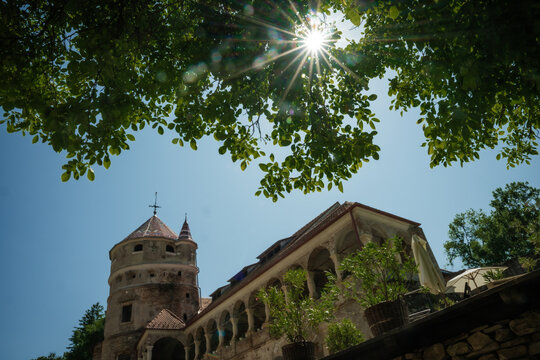 View of the ancient Bethlen Castle, with its weathered stone walls, arched windows, and the sun shining through the green leaves, Cris, Transilvania, Romania.