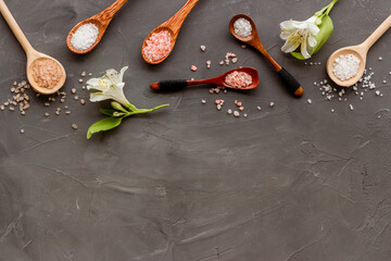 Fototapeta na wymiar Beauty spa therapy cosmetics and wellness flat lay - sea salt in many spoons with flowers, top view