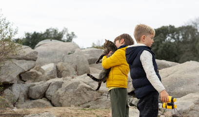 Children exploring nature with pet cat and binoculars