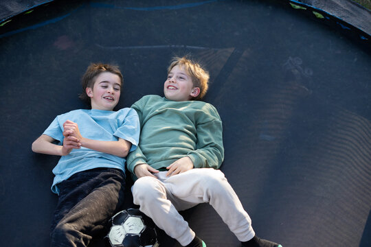 Two boys relaxing on trampoline after playing soccer