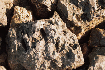 Rough natural porous stone surface texture forming a solid desert rock wall or landscape backdrop