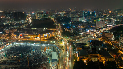 Aerial view of a vibrant cityscape with illuminated buildings, highways, and ongoing construction projects casting a warm glow, Hyderabad, Telangana, India.