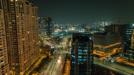 Aerial view of the gleaming city lights illuminating the modern high-rise buildings and busy roads in the night, Hyderabad, Telangana, India.