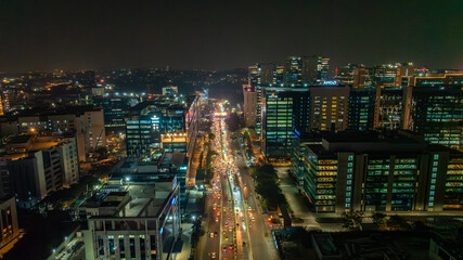 Aerial view of a bustling IT corridor illuminated with the warm glow of streetlights and building windows, creating a vibrant tapestry of urban life, Hyderabad, Telangana, India.