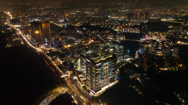 Aerial view of the city's illuminated buildings casting a golden glow against the dark canvas of night, creating a mesmerizing urban spectacle, Hyderabad, Telangana, India.