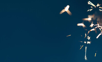 Blurred sparks from sparklers on dark backdrop with copy space. Perfect background template for holiday celebration and party-themed designs.