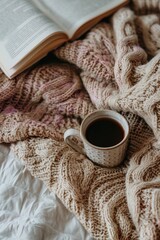 Cozy knit blanket with coffee cup and open book on relaxing morning
