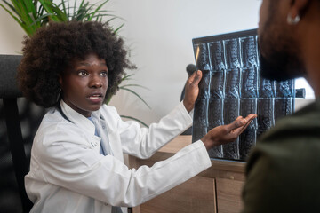Black female doctor explaining patient’s spine MRI results in clinic