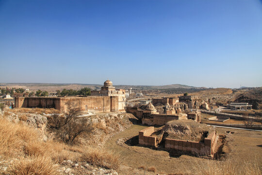 View of ancient sandstone architecture contrasts against a clear blue sky over the arid landscape, a testament to enduring history, Katas, Punjab, Pakistan.