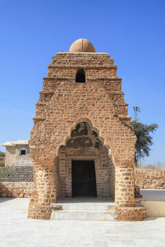 View of an ancient, weathered stone temple stands against a clear blue sky, its textured facade whispering tales of history, Katas, Punjab, Pakistan.