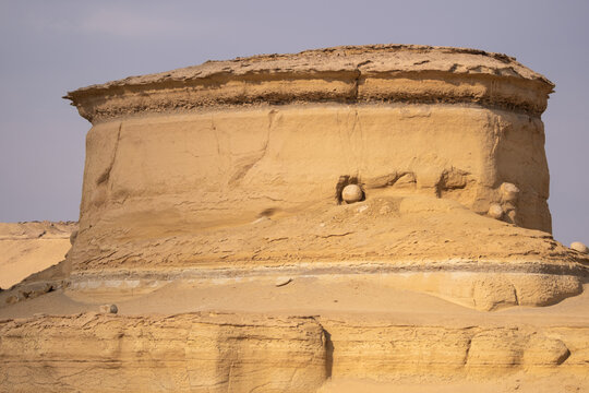 View of weathered sandstone formation with layered textures under a pale sky, sculpted by time and elements, Qaroun Protected Area, Faiyum Governorate, Egypt.